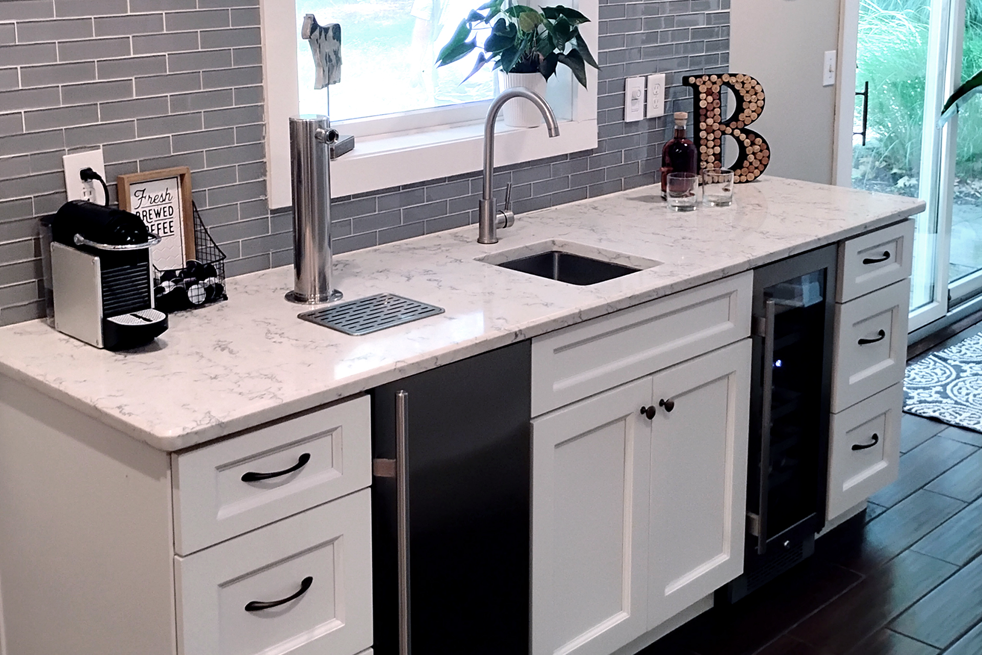Residential kitchen bar installation with keg cooler and tap and wine cooler